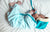 a newborn in a blue onesie asleep on a bed
