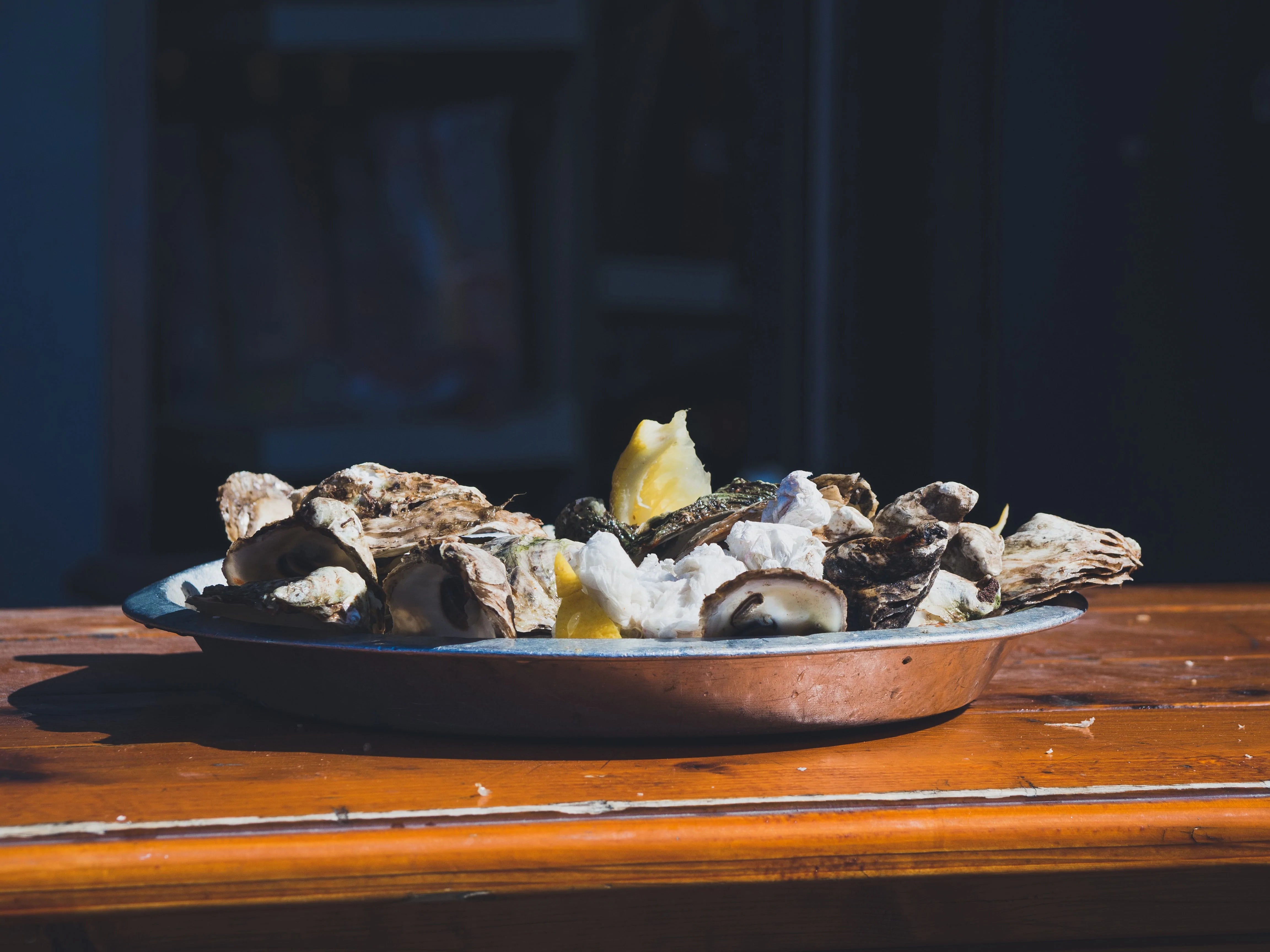 a plate of fresh oysters and lemon slices on a wooden table