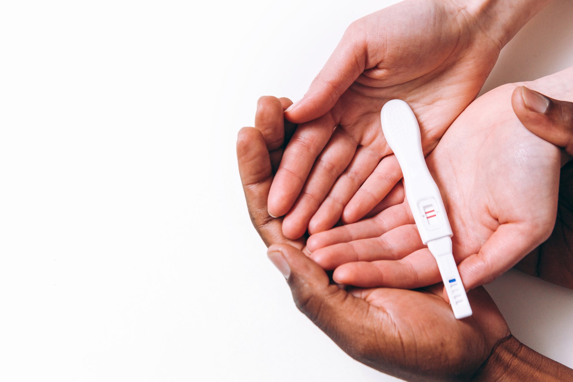 male and female hands hold positive pregnancy test