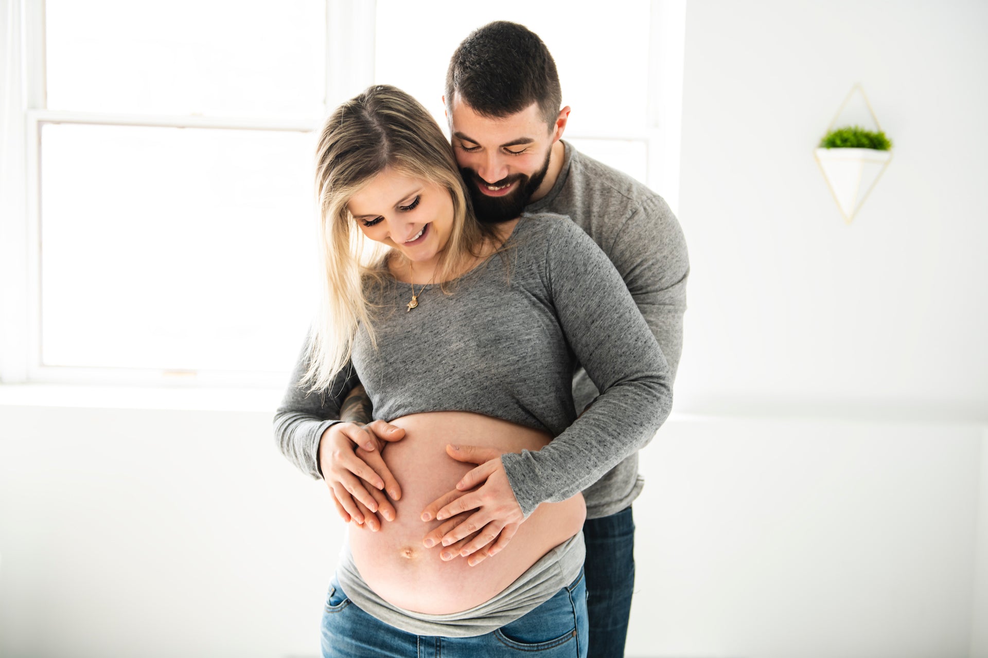 man embraces pregnant wife's belly from the back