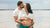husband kisses and embraces pregnant wife on the beach