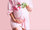 pregnant woman cradles baby bump with flowers in left hand
